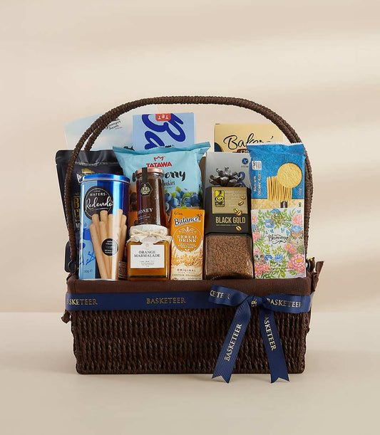 Woven dark brown gourmet gift basket with blue Basketeer ribbon, filled with honey, marmalade, coffee, wafers, and artisan