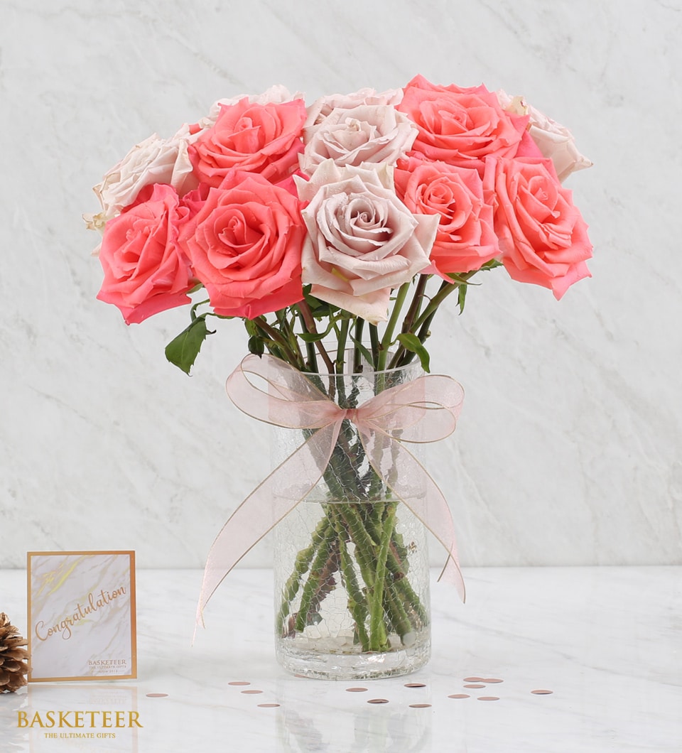 Fresh coral and dusty rose bouquet in clear glass vase with pink ribbon bow