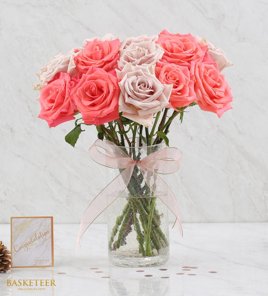 Fresh coral and dusty rose bouquet in clear glass vase with pink ribbon bow