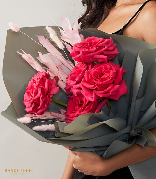 Vibrant pink rose bouquet with preserved foliage, wrapped in dark grey-green paper for Valentine's Day