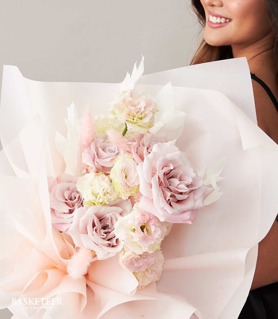 Blush pink rose bouquet with cream accents, wrapped in soft peach paper for Valentine's Day gifts