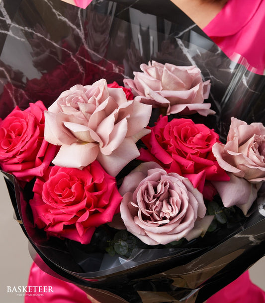 Pink and magenta rose bouquet with dusty rose accents, wrapped in marble-patterned black paper for anniversaries