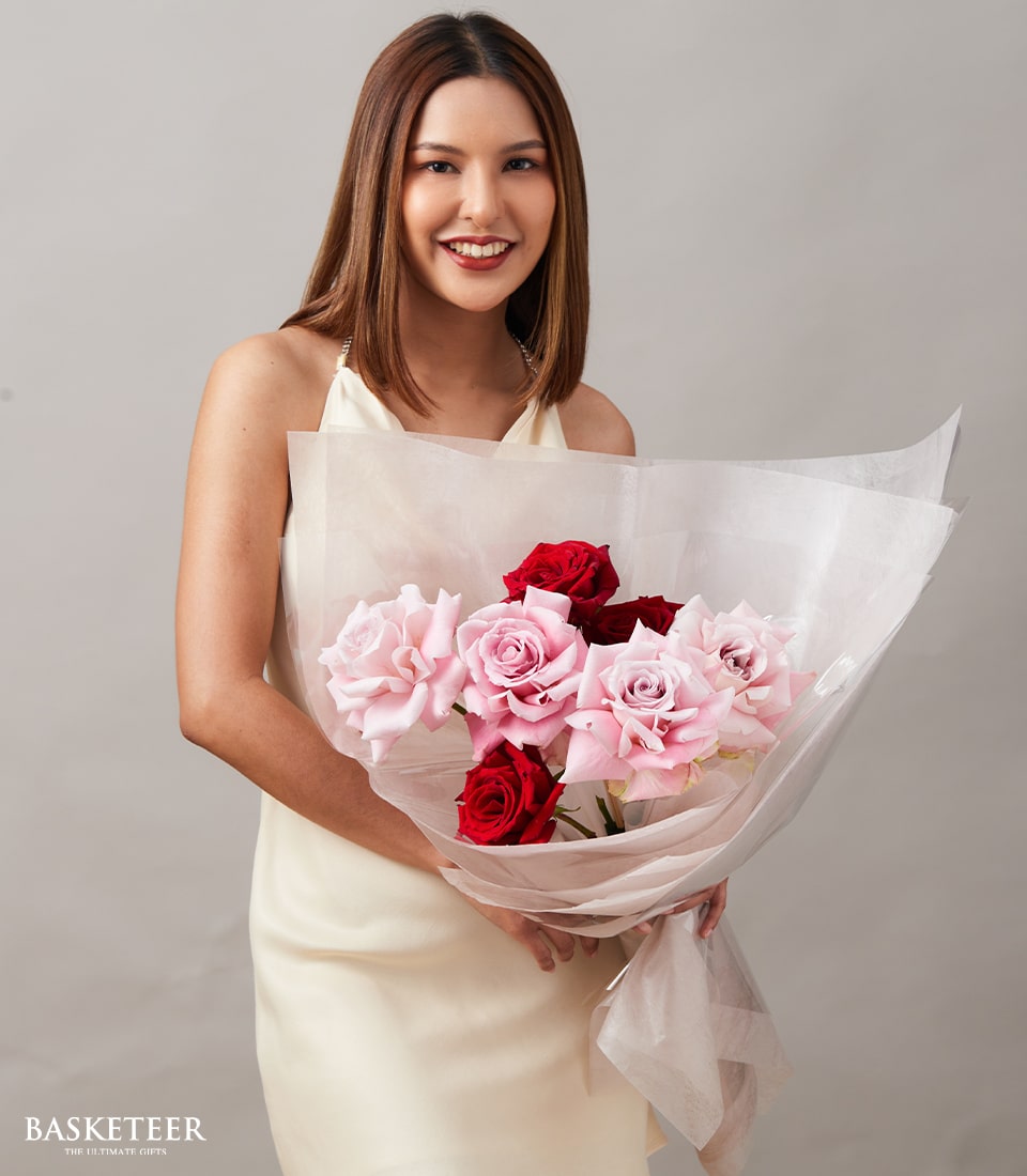 Blush and crimson rose bouquet held by woman in cream dress, premium Ecuador roses wrapped in pink tissue paper for