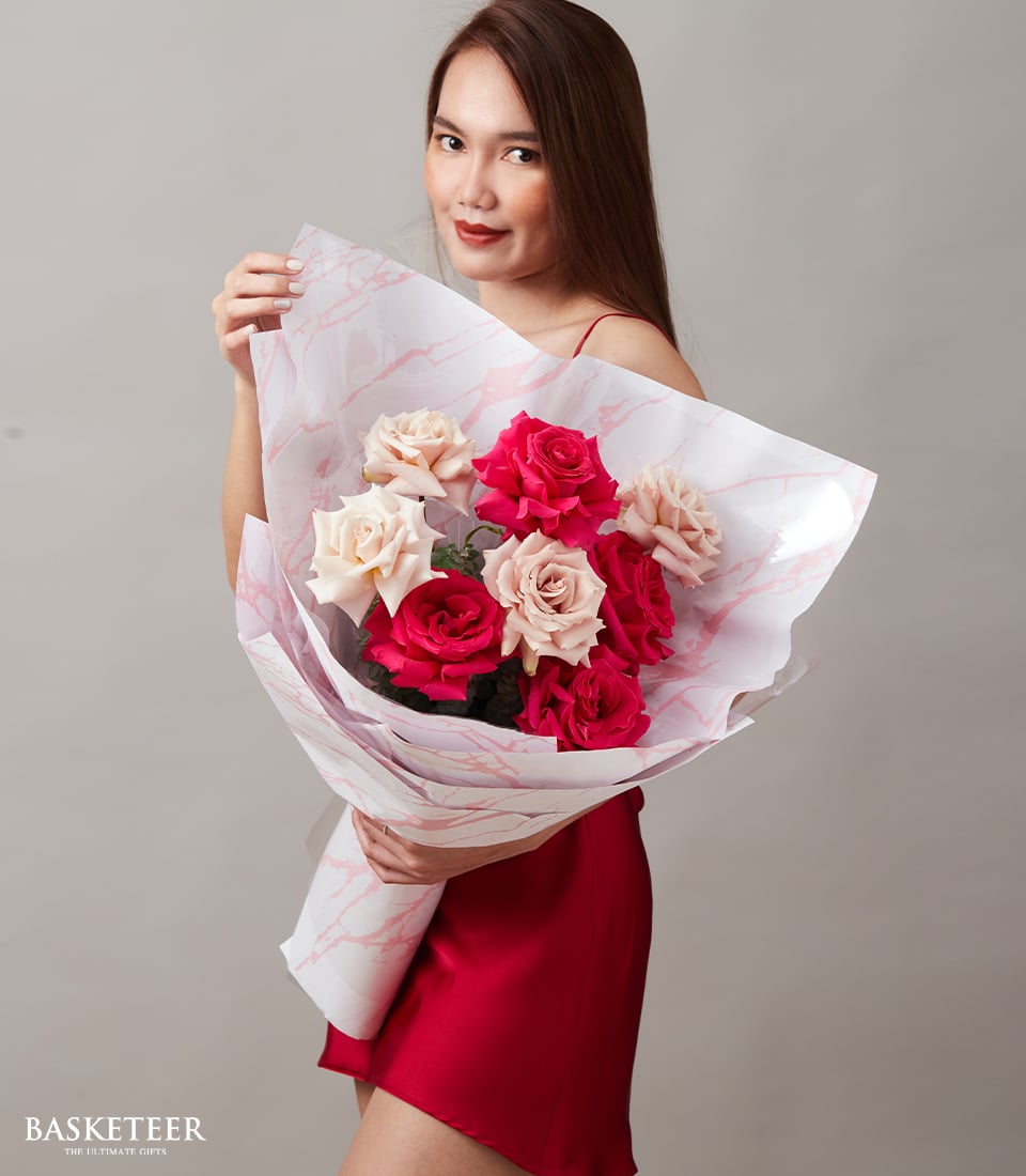 Woman holding fuchsia and peach rose bouquet wrapped in marble paper for anniversary
