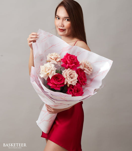 Woman holding fuchsia and peach rose bouquet wrapped in marble paper for anniversary