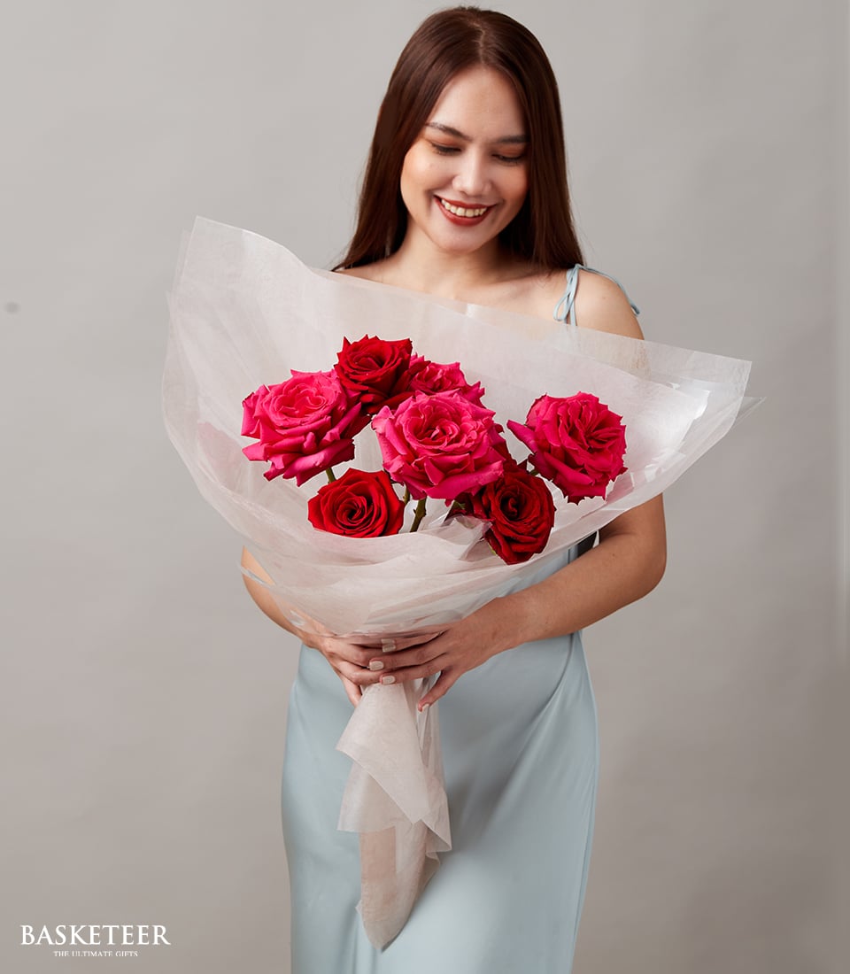 Woman holding luxurious red and fuchsia rose bouquet wrapped in sheer pink paper, perfect Valentine's Day gift for her