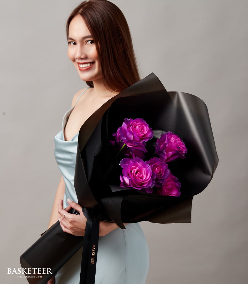 Vibrant purple rose bouquet wrapped in black paper with gold ribbon, perfect for graduation gifts