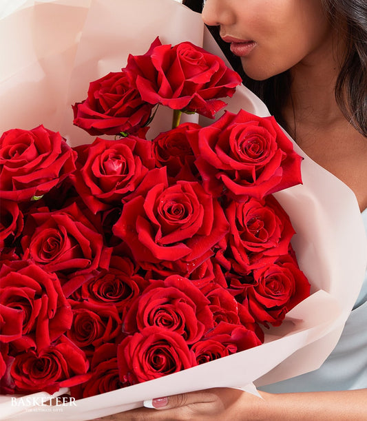 Luxe red rose bouquet with fresh water droplets, wrapped in soft pink paper for anniversaries and romance
