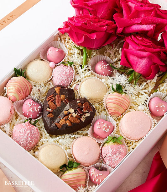 Luxury Valentine's gift box with fresh pink roses, chocolate-dipped strawberries, macarons, and heart-shaped chocolates