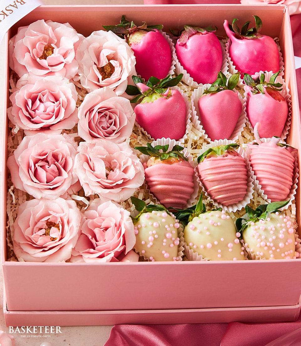 Blush pink gift box with twelve roses and chocolate-covered strawberries in fuchsia, pink drizzle, and white pearl styles