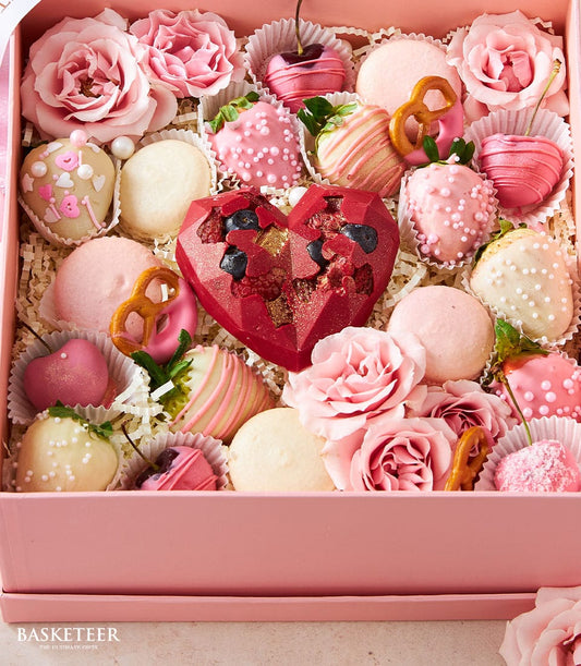 Pink luxury valentine gift box with chocolate-covered strawberries, macarons, heart truffles, and fresh roses