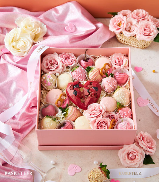 Luxury pink Valentine's Day gift box with chocolate-covered strawberries, macarons, and ruby heart centrepiece