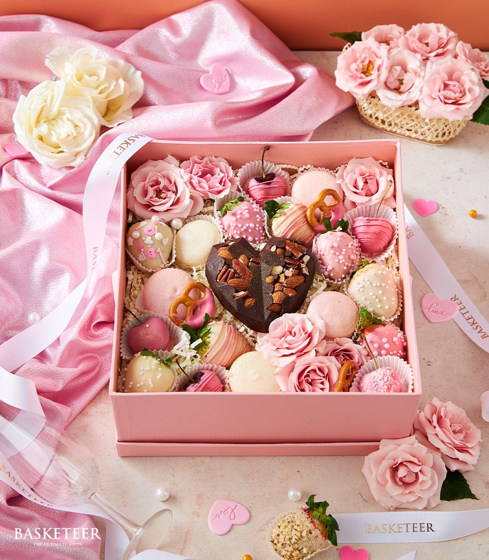 Luxury pink chocolate and treats gift box with strawberries, macarons, and fresh roses for Valentine's Day