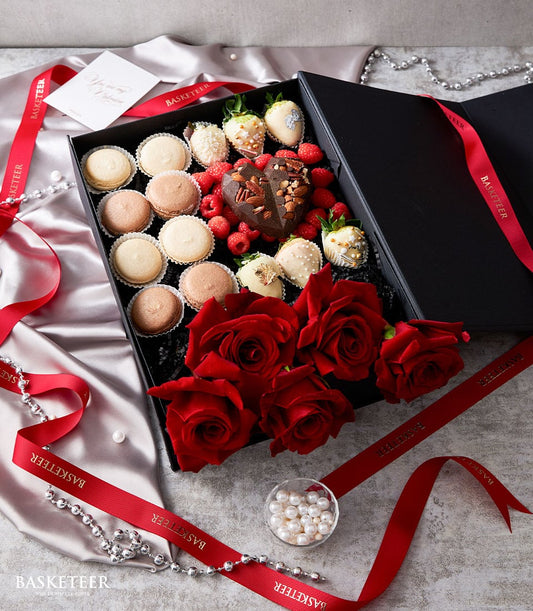 Luxury Valentine's gift box with fresh red roses, chocolate-covered strawberries, macarons, and heart-shaped chocolate