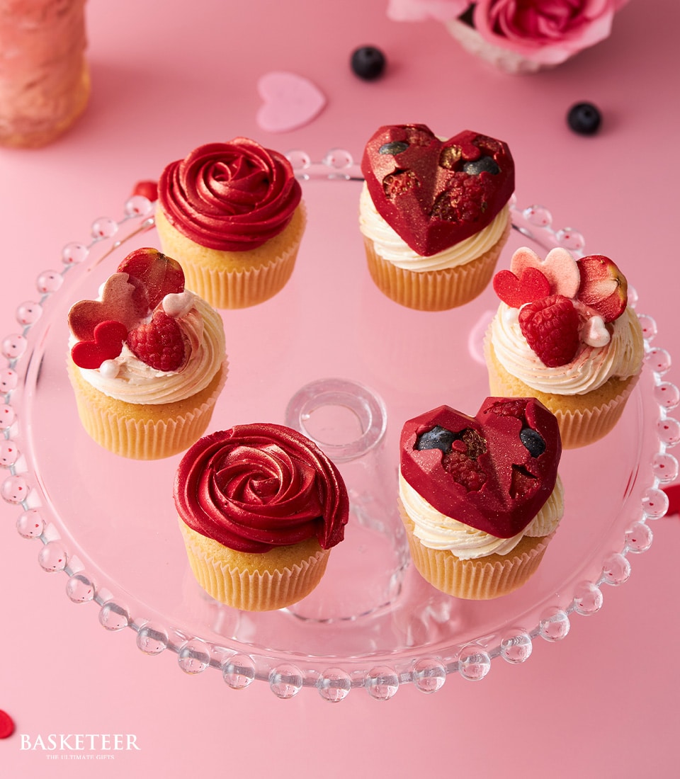Romantic red and white Valentine's Day cupcakes with chocolate hearts and fresh berries on glass stand
