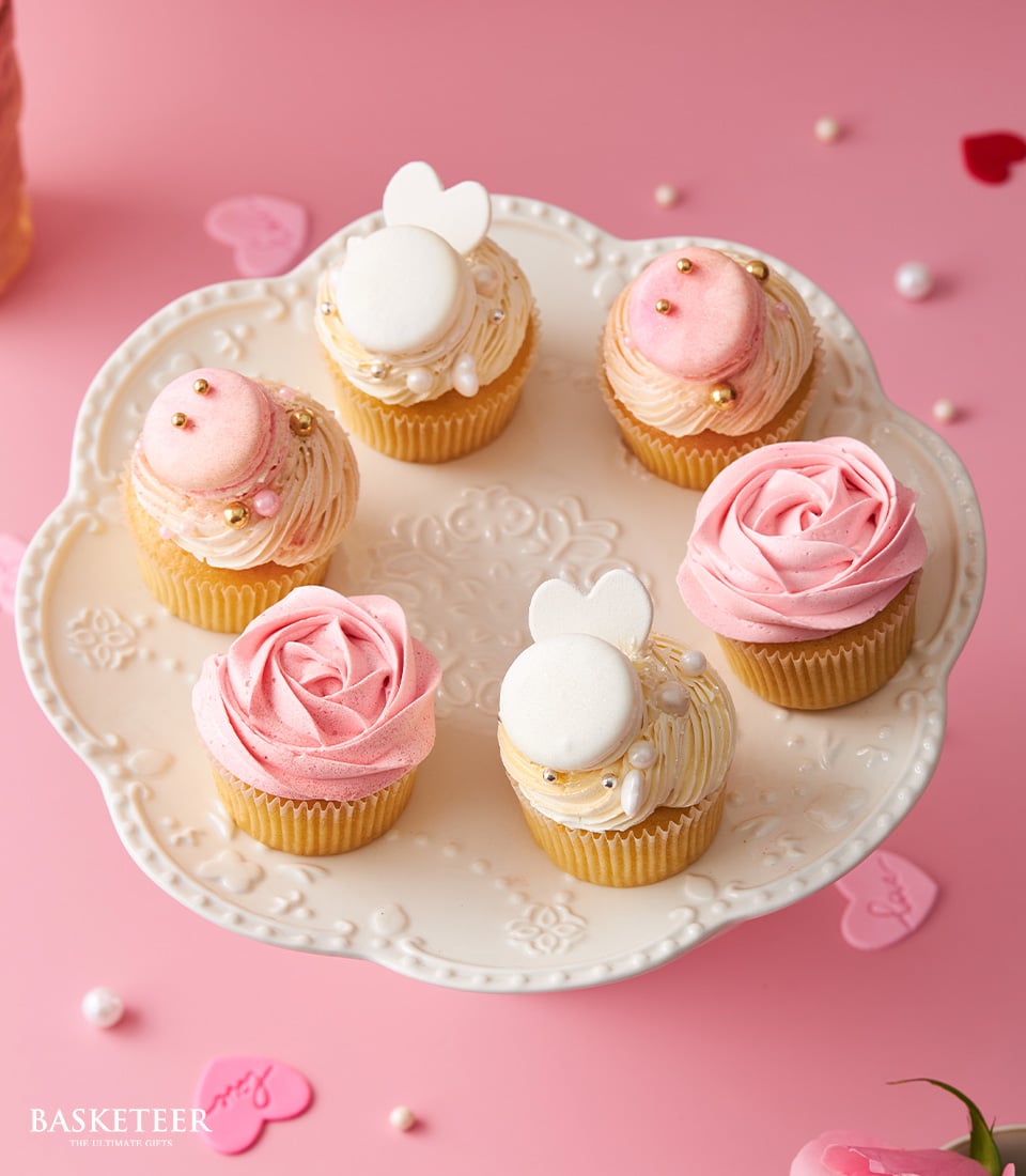 Elegant vanilla cupcake set with pink and white frosting, rose swirls, and gold accents on ornate stand for Valentine's Day