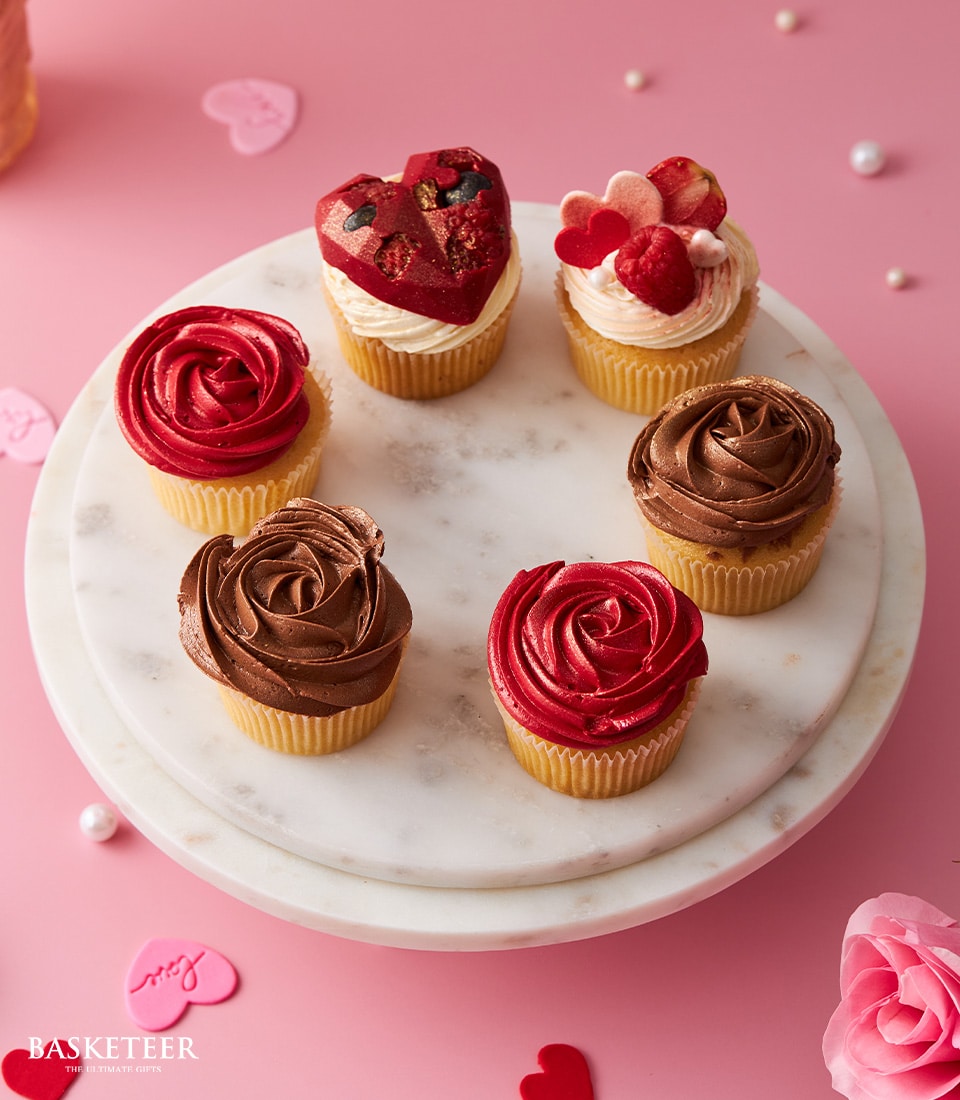 Artisan Valentine's cupcakes with red rose and heart chocolate toppings on marble stand