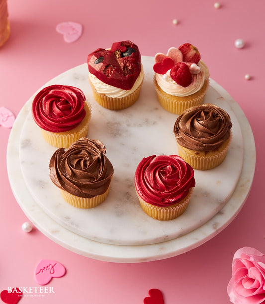 Artisan Valentine's cupcakes with red rose and heart chocolate toppings on marble stand