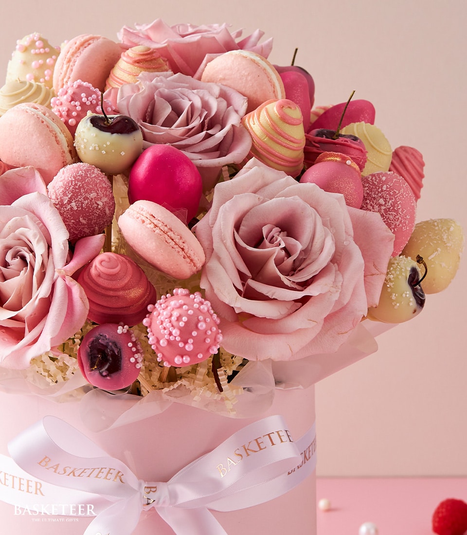 Pink roses, macarons, and chocolate-covered strawberries in luxury Valentine's gift box