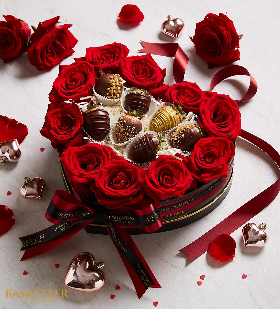 Heart-shaped gift box with red roses and chocolate-covered strawberries, black and gold striped packaging with black ribbon