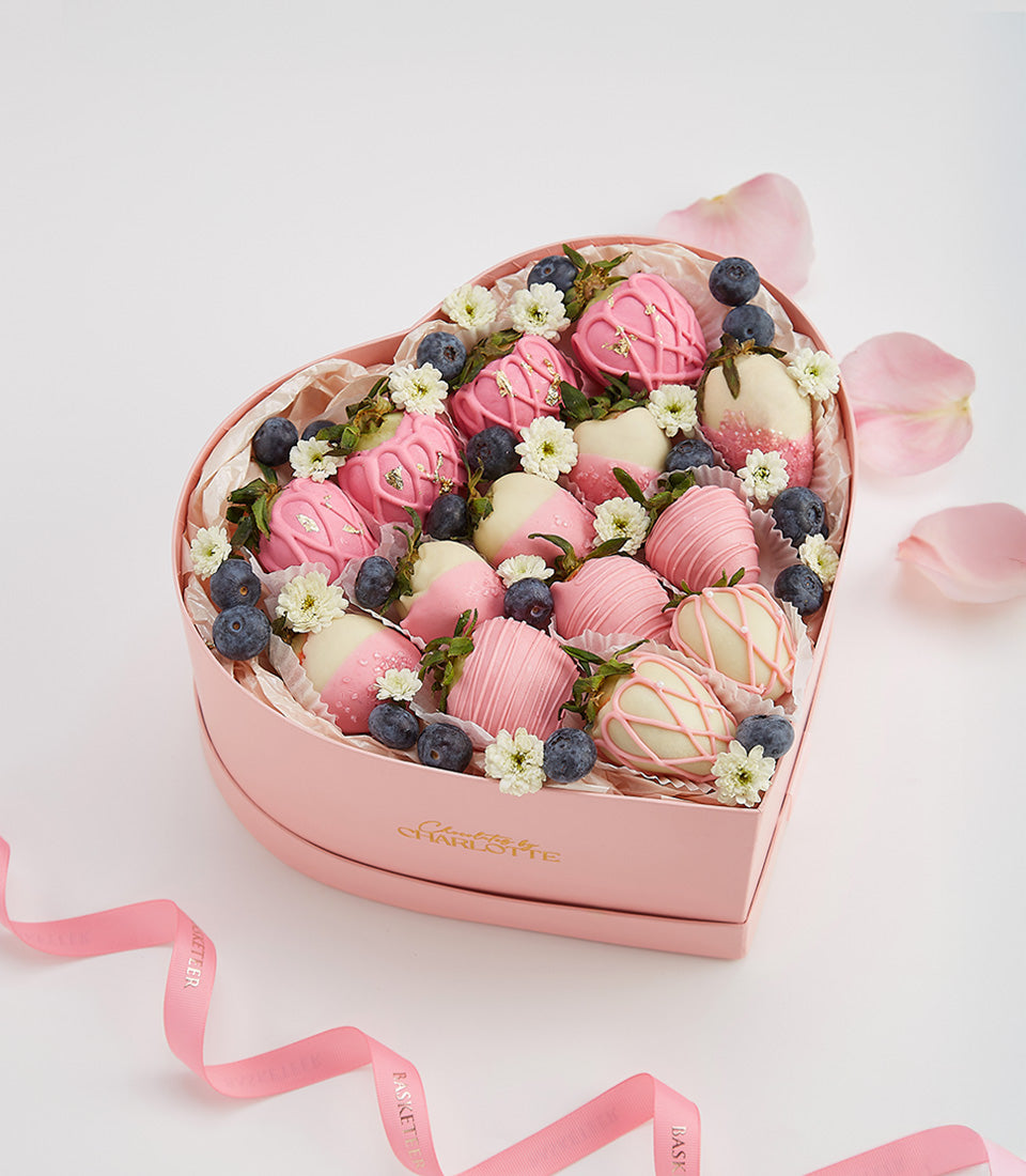 Heart-shaped gift box with chocolate-covered strawberries, blueberries, and edible flowers for Valentine's Day