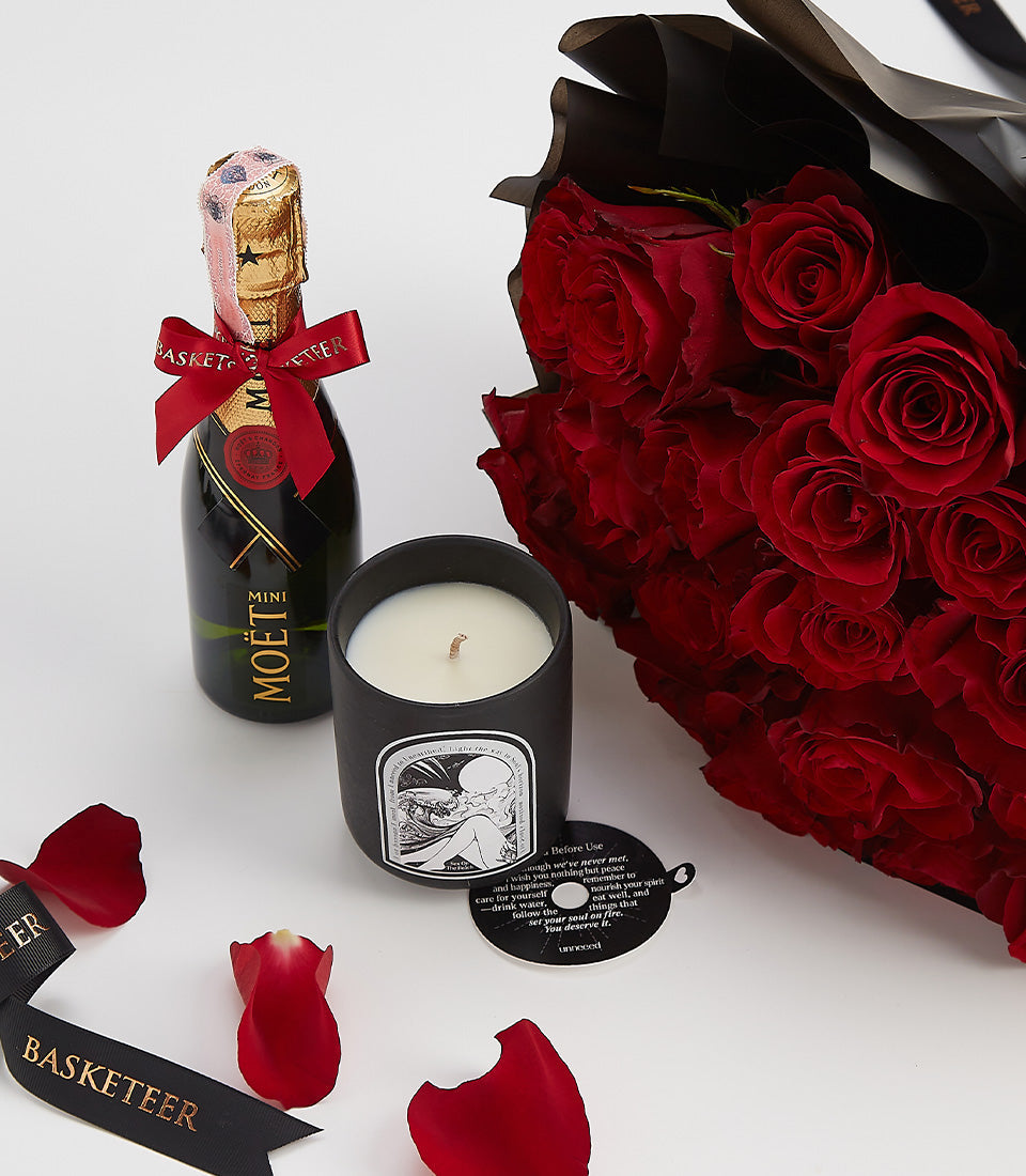 Luxury Valentine gift set with champagne, red roses, and black candle on white background