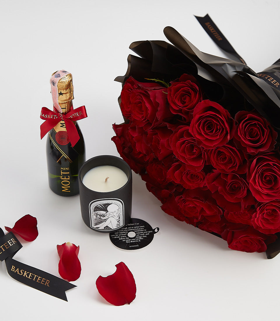 Luxury Valentine gift set with deep red roses, champagne, and black candle with gold accents