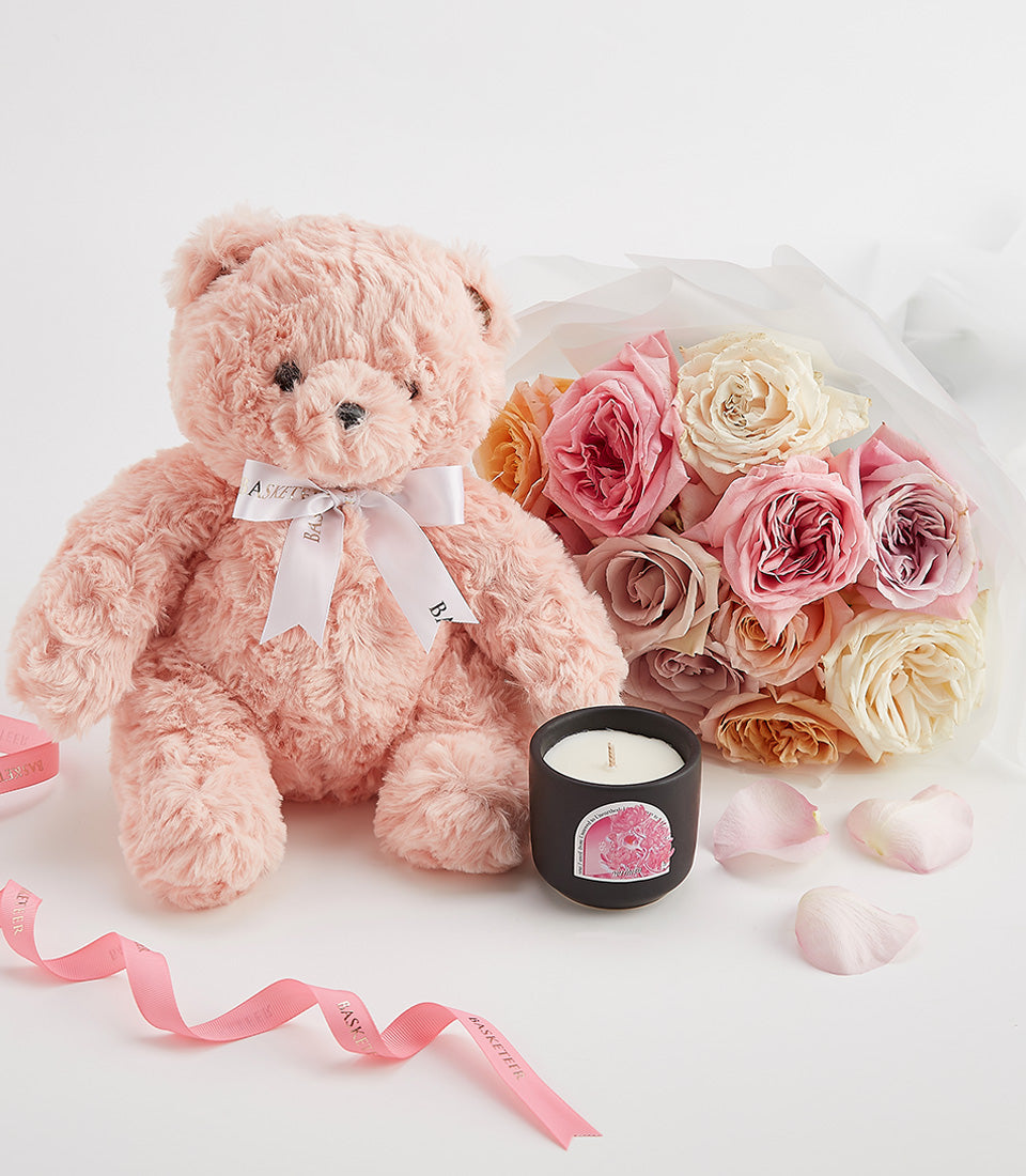 Fluffy pink teddy bear with pastel roses, scented candle, and rose petals Valentine's Day gift set