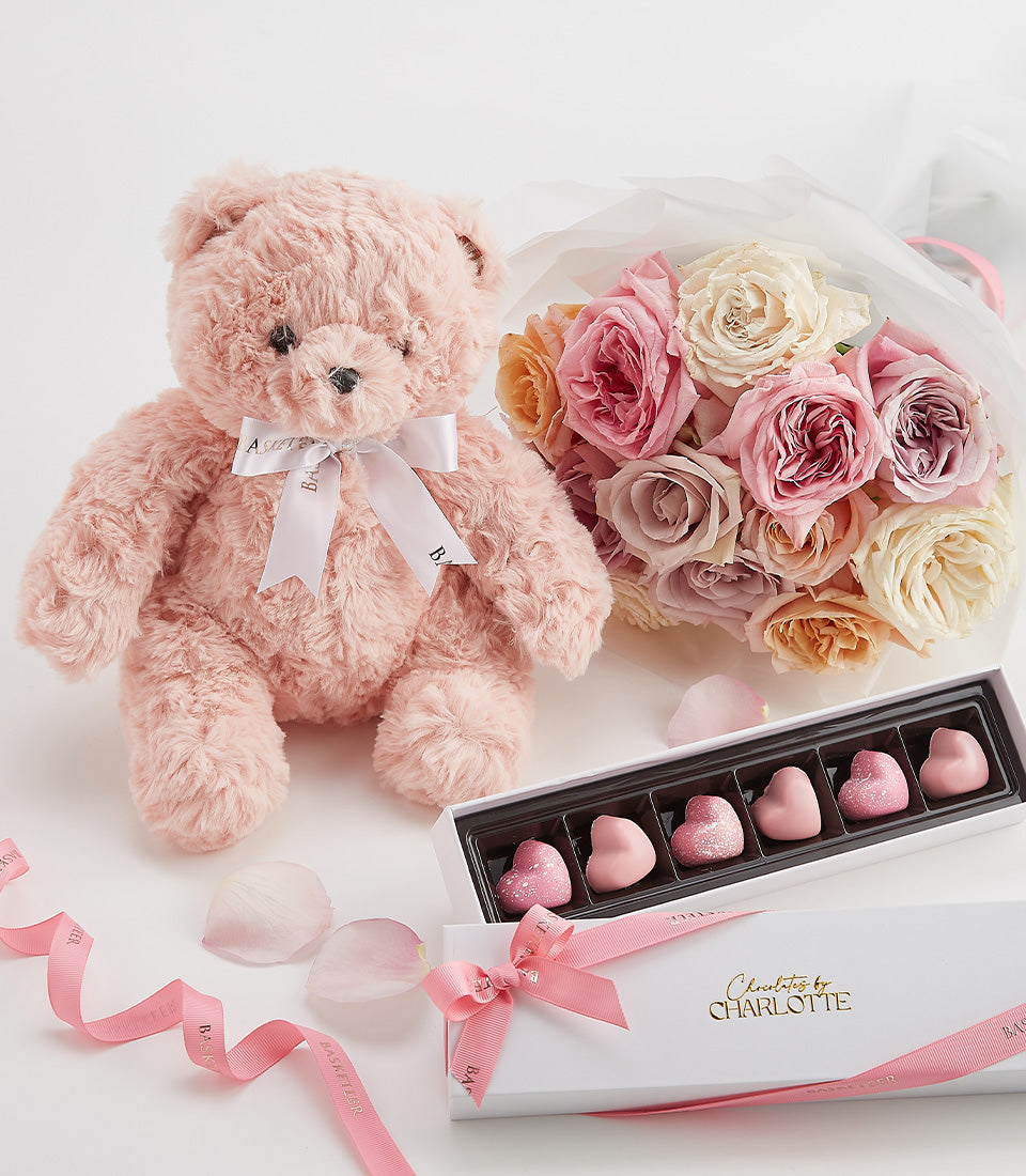 Romantic Valentine's Day gift bundle with pink teddy bear, rose bouquet, and heart-shaped chocolates by Charlotte