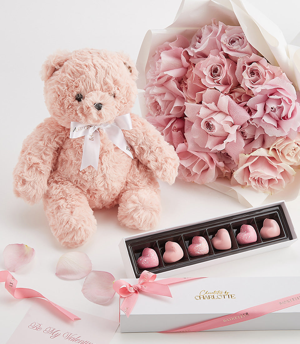 Pink roses, chocolates, and teddy bear Valentine's Day gift set with white packaging and rose petals