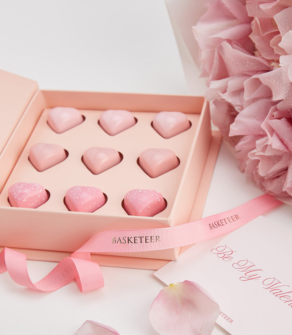 Luxury Valentine's Day gift set with heart-shaped chocolates, pink ribbon, and fresh flowers from Basketeer