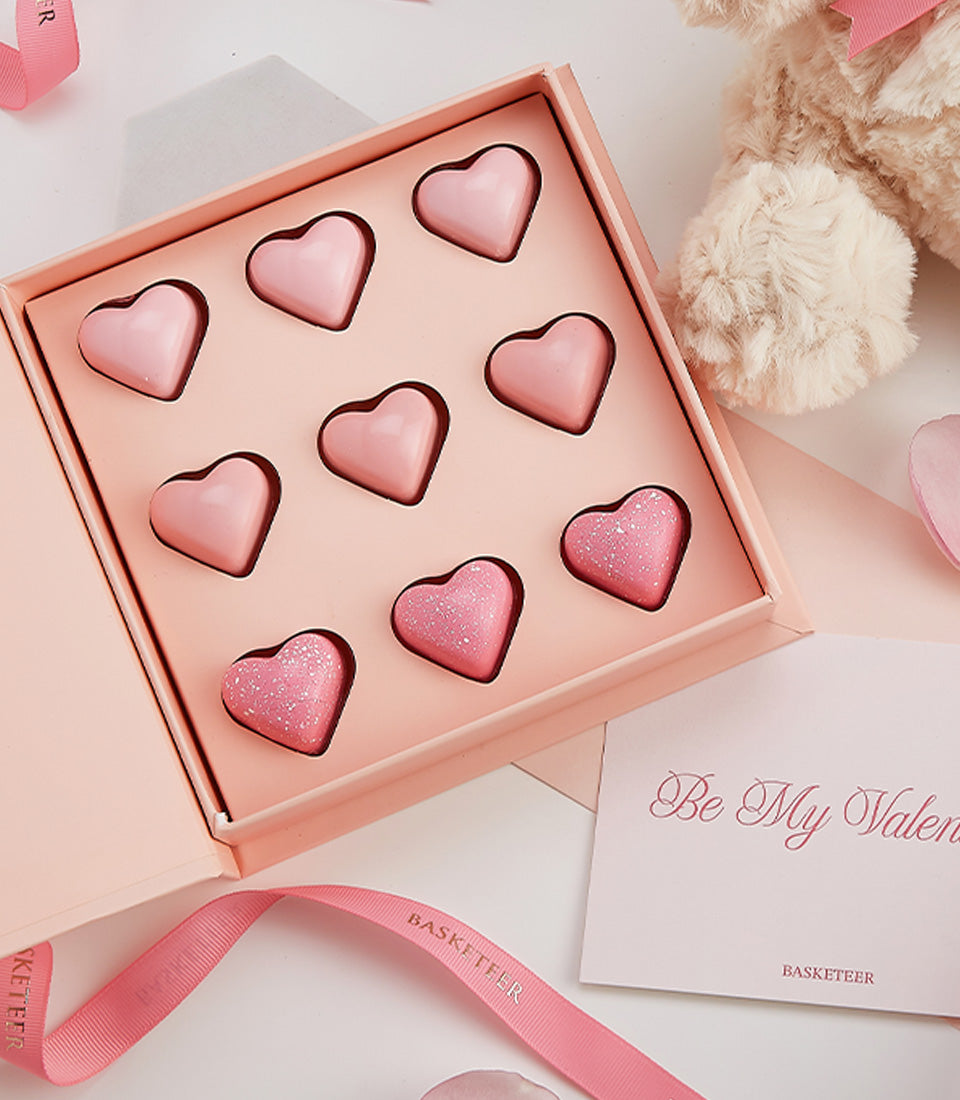 Rosé pink gift box with heart-shaped chocolates and Valentine card for luxury romantic gifting