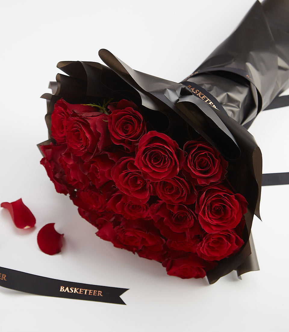 Deep red rose bouquet wrapped in matte black paper with gold ribbon for Valentine's Day