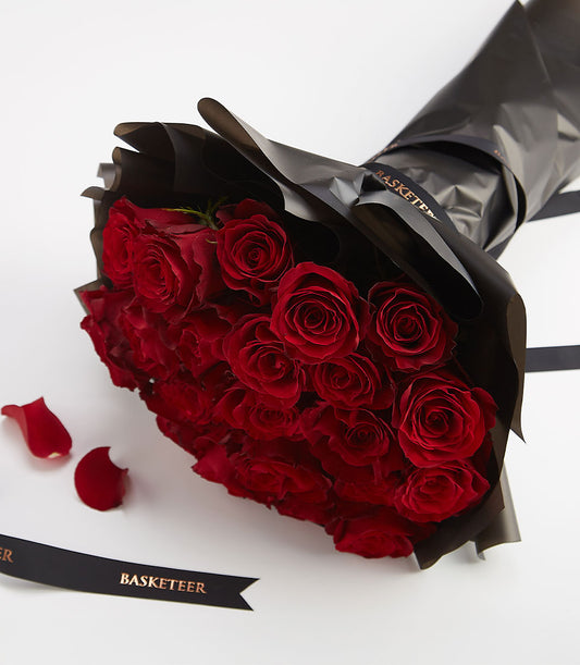 Deep red rose bouquet wrapped in matte black paper with gold ribbon for Valentine's Day