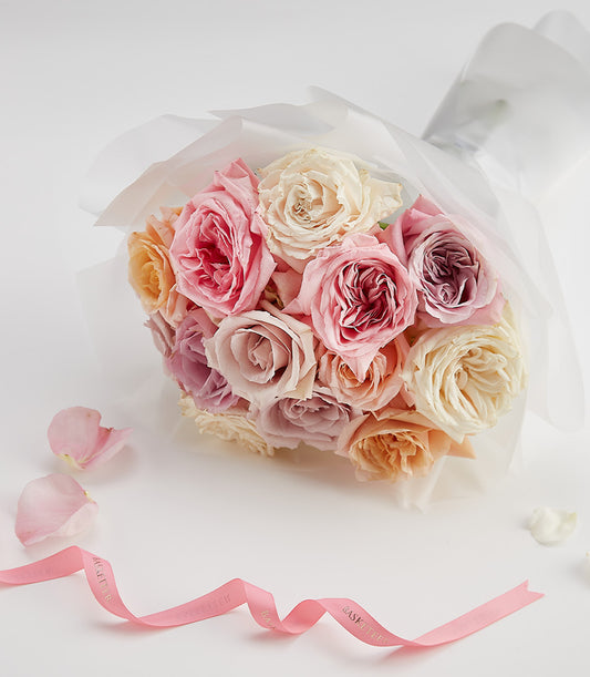 Pastel rose bouquet in blush, peach, cream and mauve with white wrapping for anniversaries and Valentine's