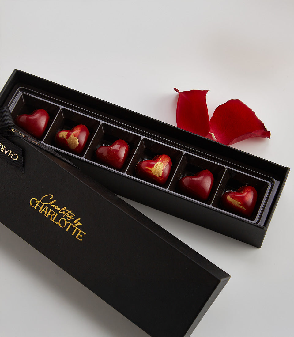Red heart-shaped liquor chocolates in luxury black gift box with gold accents, six-piece Valentine's set