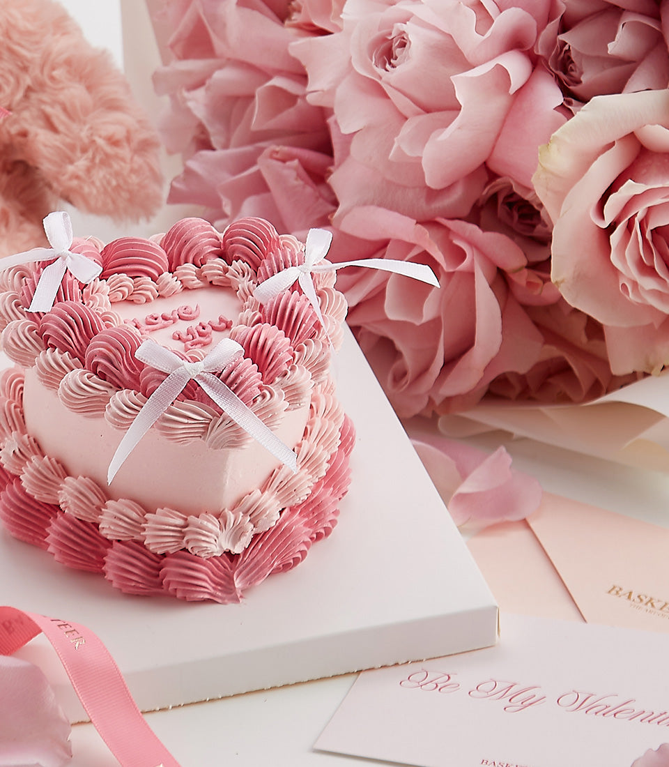 Heart-shaped Valentine's cake with pink roses, petals, and romantic gift set for couples