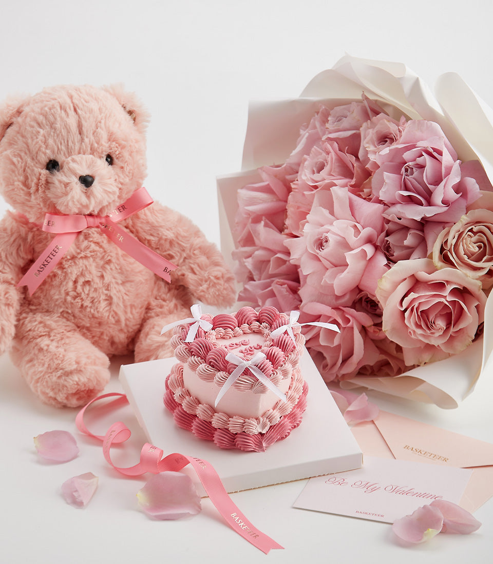 Pink Valentine's gift set with teddy bear, heart-shaped cake, and fresh roses with love card