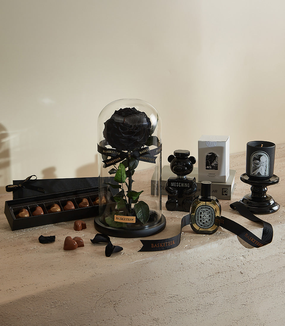 Luxury Valentine gift set with preserved black rose under glass dome, heart chocolates, perfume, and black candle