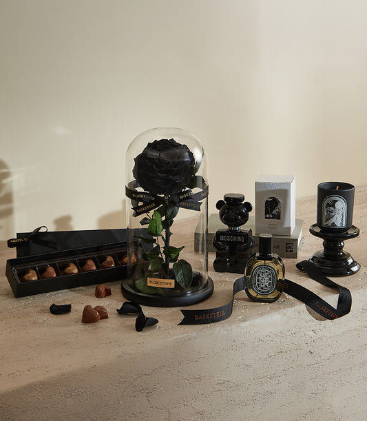 Luxury Valentine gift set with preserved black rose under glass dome, heart chocolates, perfume, and black candle