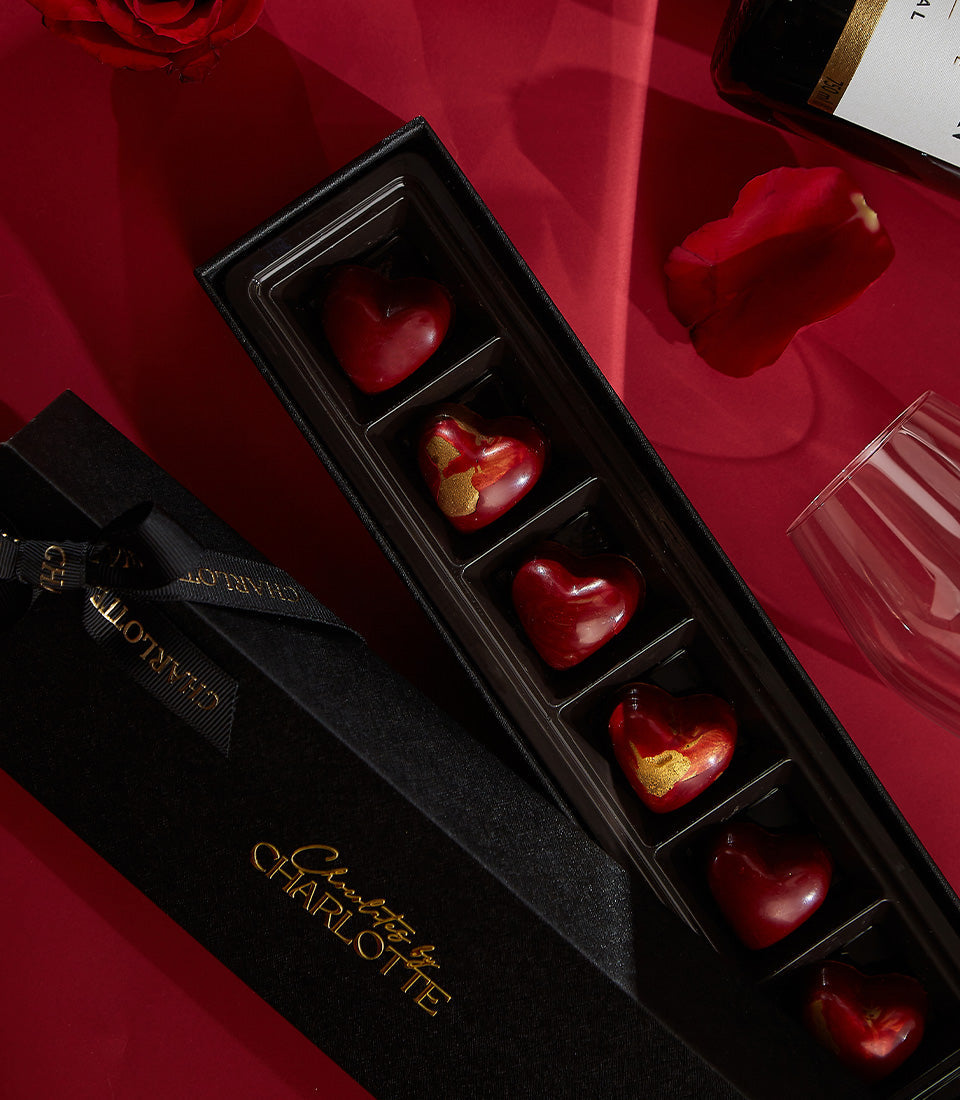 Luxury Valentine's Day gift set with champagne, heart-shaped dark chocolates, and fresh red roses