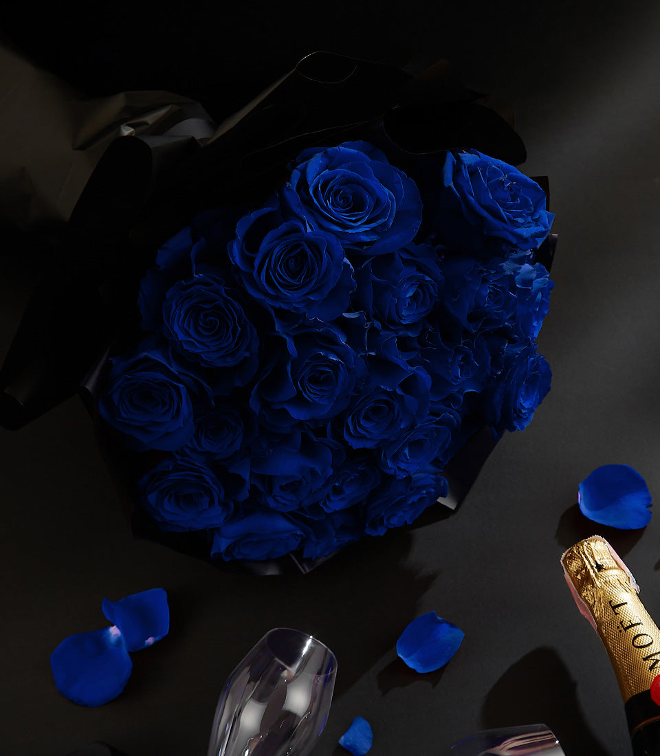 Luxury champagne gift with deep blue roses, champagne flutes, and gold-foil bottle for Valentine's celebration