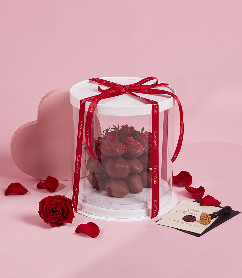 Luxury dark chocolate-covered strawberries with raspberry sprinkles in elegant gift box with red Charlotte ribbon,