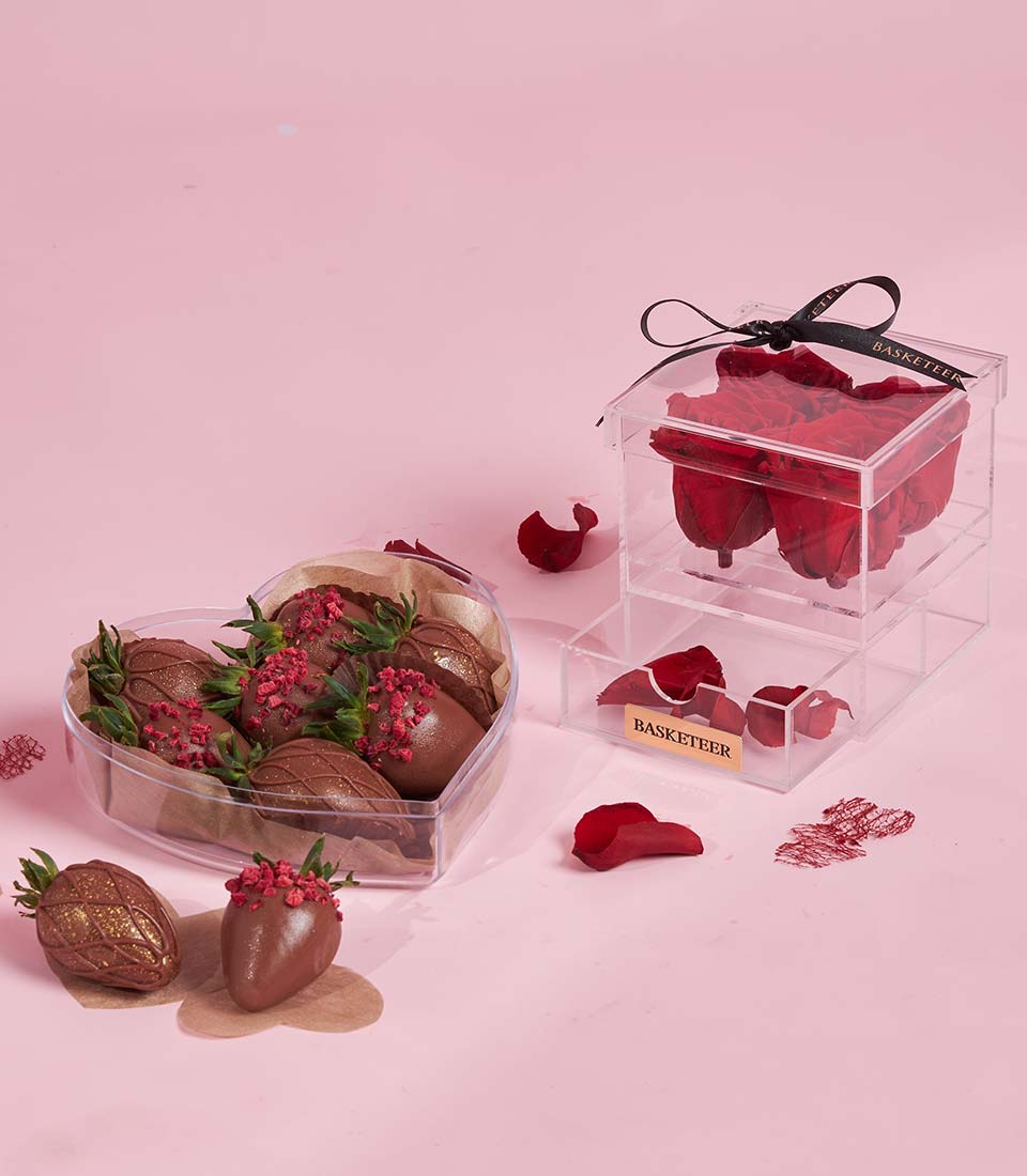 Romantic Valentine gift set with chocolate-covered strawberries and preserved red roses with black ribbon