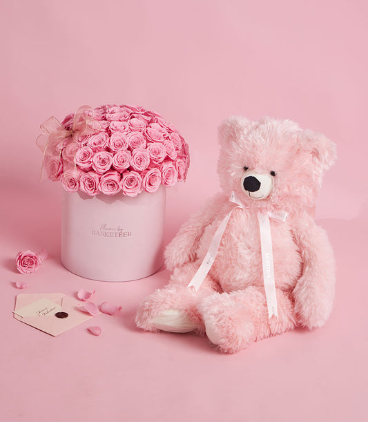 Flowers by Basketeer preserved pink rose arrangement in a hat box, paired with a plush pink teddy bear. Perfect for flower delivery Bangkok.