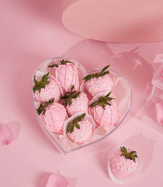 Heart-shaped box of chocolate-covered strawberries with pink icing and white sprinkles for Valentine's Day