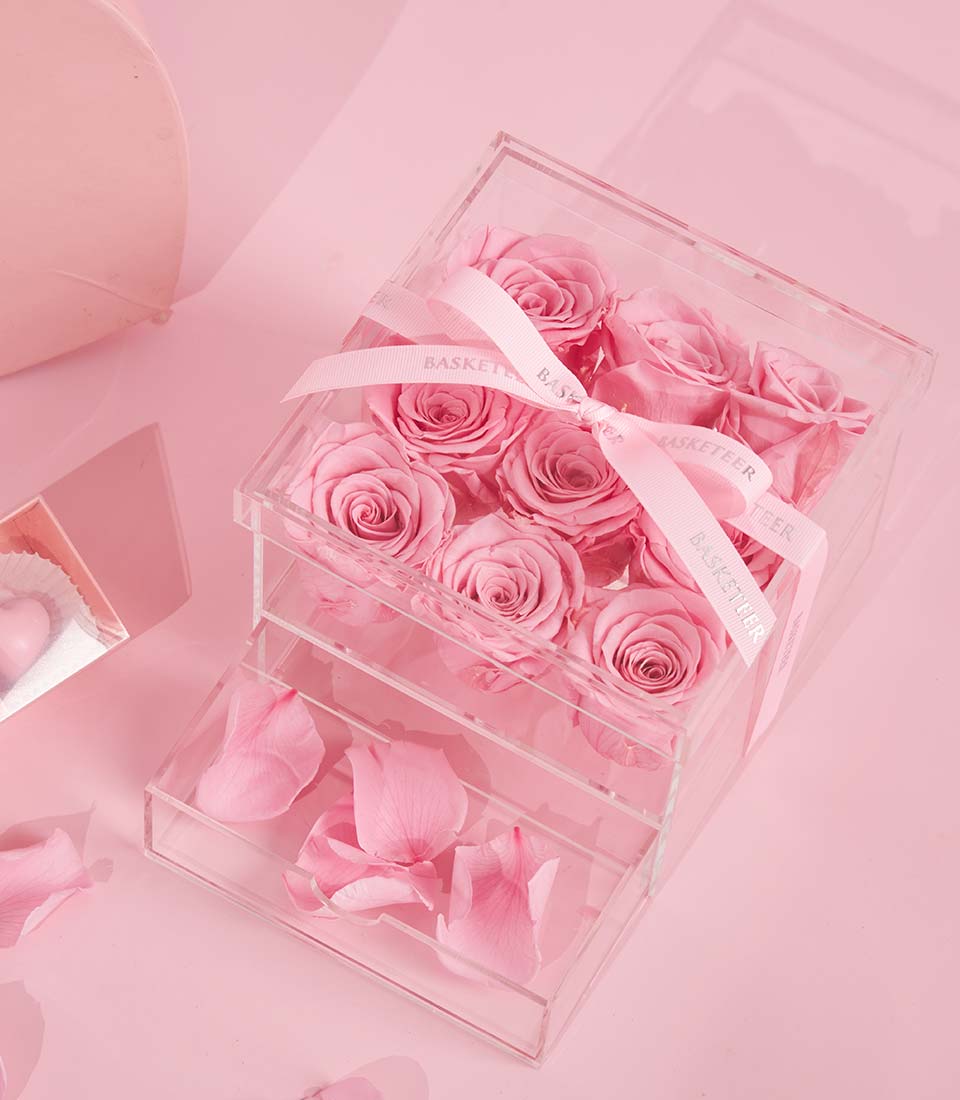 Charlotte Bakery gift set: a clear box of nine pink roses tied with ribbon, plus a box of raspberry bonbons. Perfect custom cake Bangkok pairing.