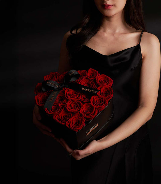 Luxury red preserved rose heart box with gold plaque, held by woman in black dress, Valentine gift