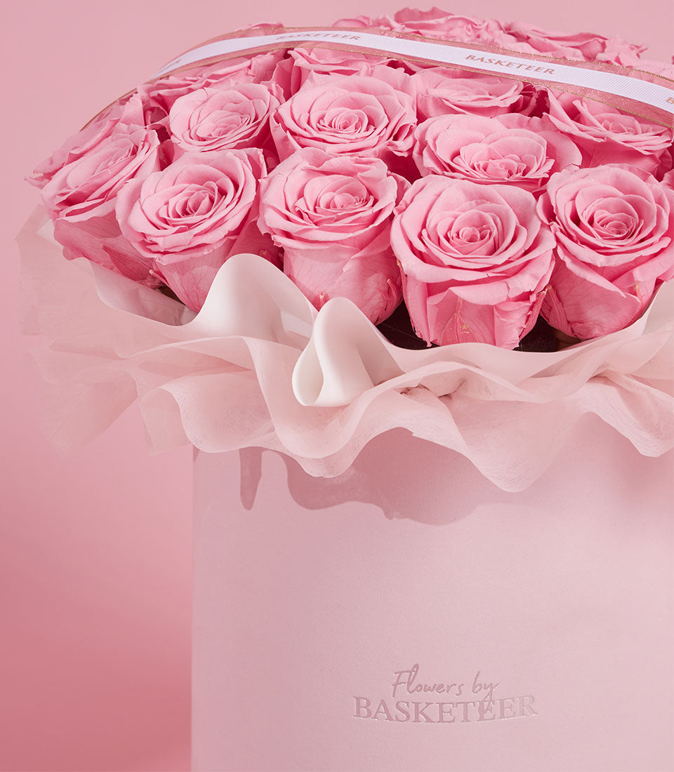 Elegant round VIP box of preserved pink roses with white ribbon and tissue, Valentine's gift from Flowers by Basketeer