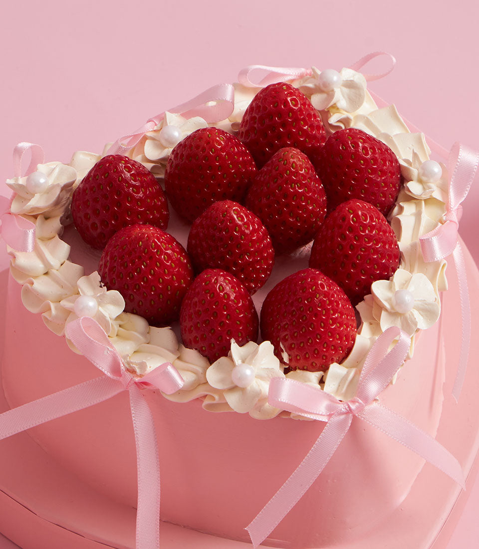 Fresh strawberry artisan cake from Charlotte Bakery, a perfect birthday cake delivery in Bangkok. Pink cream cheese frosting, ribbon detail, and pearl accents.